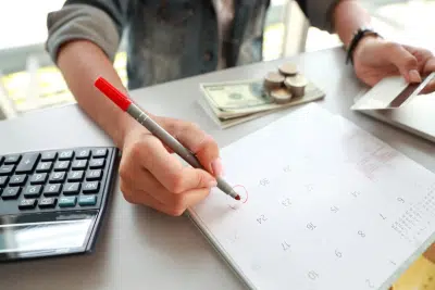 Persona marcando una fecha en el calendario junto a una calculadora
